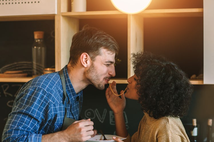 A happy couple smiles and eats spaghetti like the iconic scene from 'Lady and the Tramp.'
