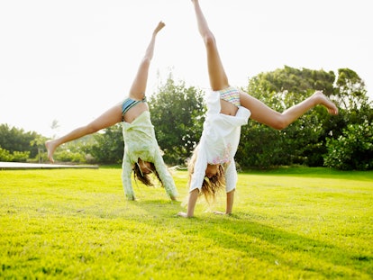 Two women cartwheel over a lawn to enjoy the sunny days.