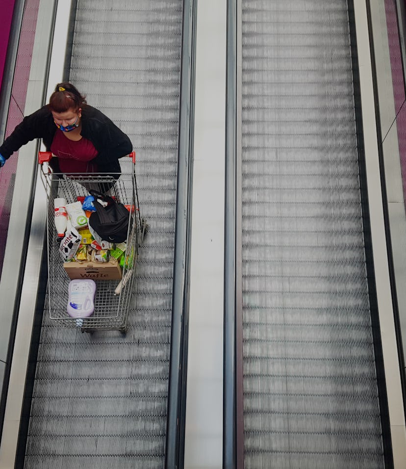 Woman with a shopping cart on a walking escalator.  