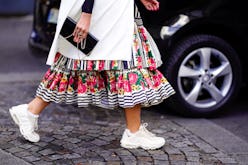 A woman walking and wearing a colorful dress and comfortable and chic sneakers