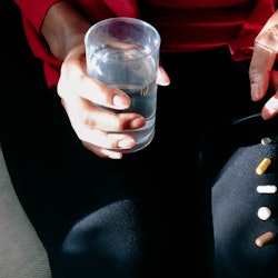 A woman with a glass of water and a row of vitamins on her leg. Experts explain how dry january may ...