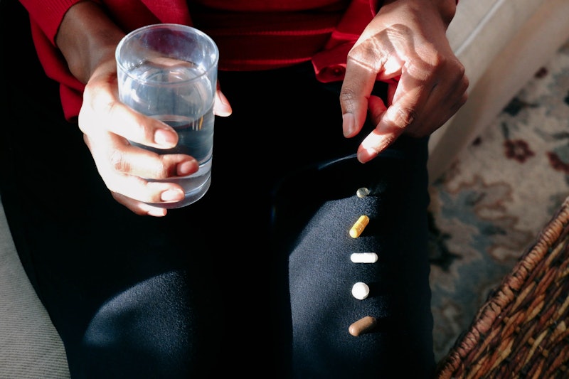 A woman with a glass of water and a row of vitamins on her leg. Experts explain how dry january may ...