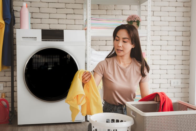 A woman sorts laundry in a bright laundry room.