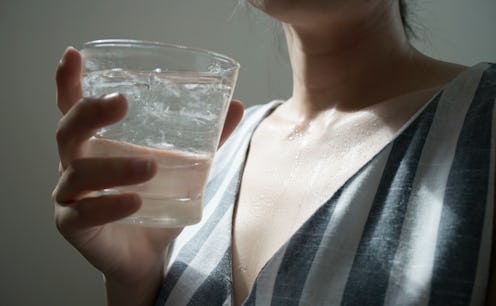 A woman drinks a glass of water. Here's what to expect from Dry January