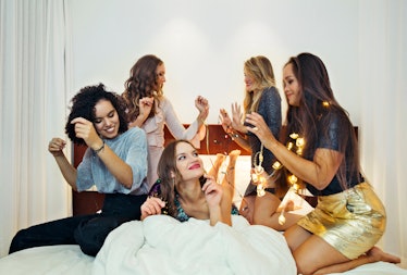 A group of fancy friends dance on the bed for a fun filled night in glitter and fairy lights.