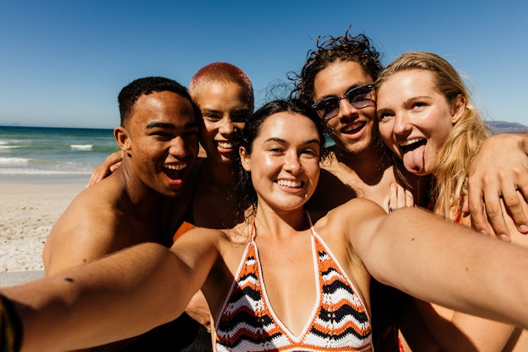 A group of friends takes a selfie on the beach while on vacation before quarantine.