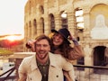 A couple poses by the Colosseum in Italy on vacation. 