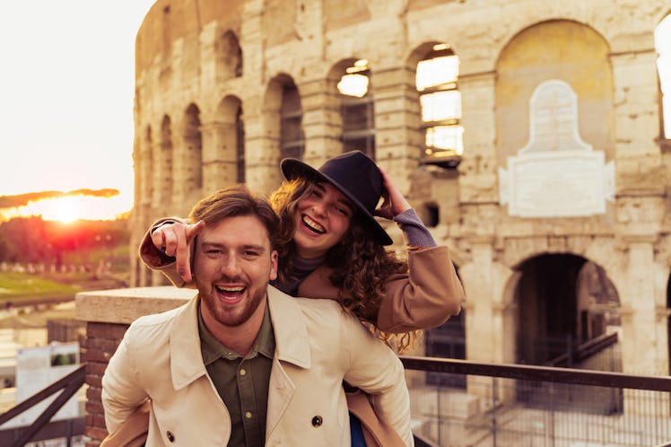 A couple poses by the Colosseum in Italy on vacation.