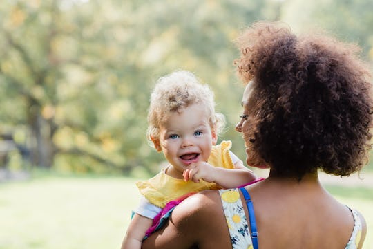 baby girl looking over her mom's shoulder