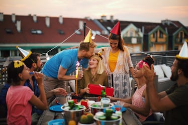 Friends at a birthday party celebrate with a cake. 