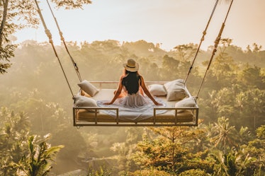 A young woman sits on a bed over the jungle in Bali, which some might consider a dream vacation on T...