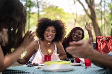 A birthday girl celebrates at her picnic party in the park with her friends. 