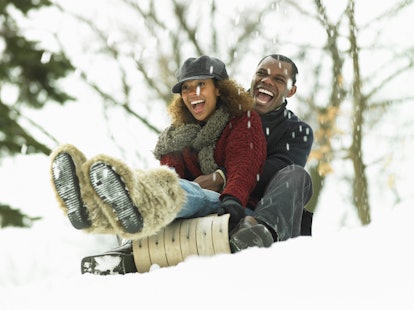 A young couple goes sledding in their backyard on winter day.