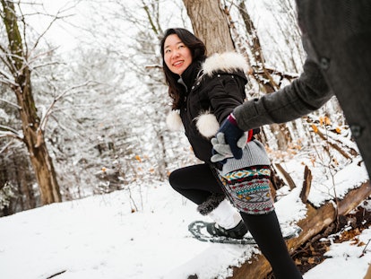 A young couple goes snowshoeing in their backyard on a winter day.