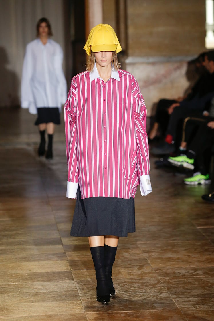 A model walking in a red-white shirt and black skirt at the Raf Simons Ready to Wear Spring/Summer 2...