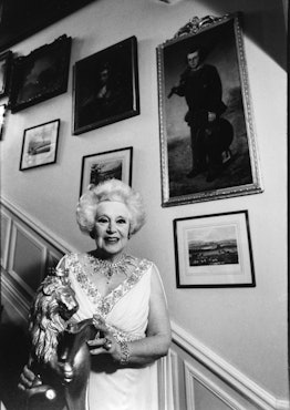 Dame Barbara Cartland (1901-2000) English author of romance novels, on the staircase of her home in ...