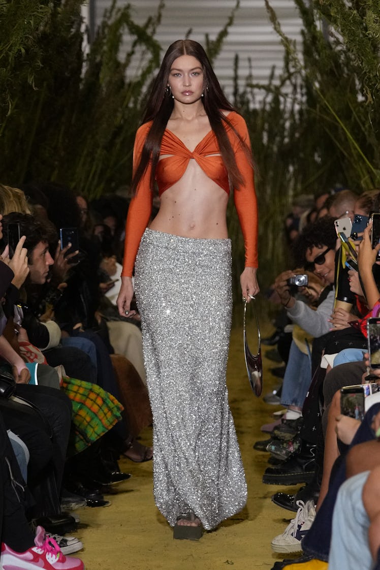 A model walking in an orange top and silver sequin skirt at the Coperni Womenswear Spring/Summer 202...