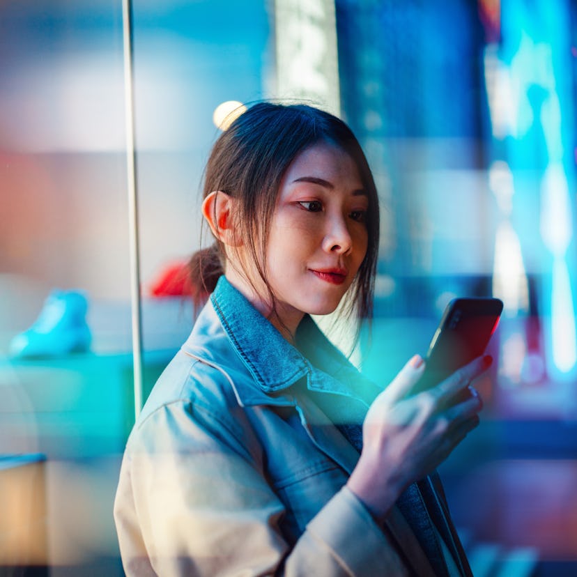 Woman checking her phone, wondering if her zodiac sign will have the best November 2021 new moon in ...