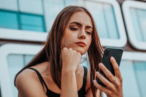 Reading Bad News on Mobile Phone. Young teenage woman checking her messages and social media post on...