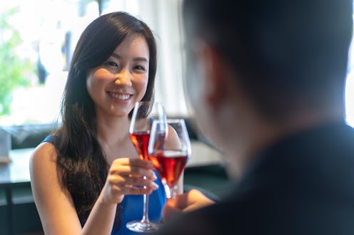 Beautiful young Asian woman having a toast with her partner at a restaurant.