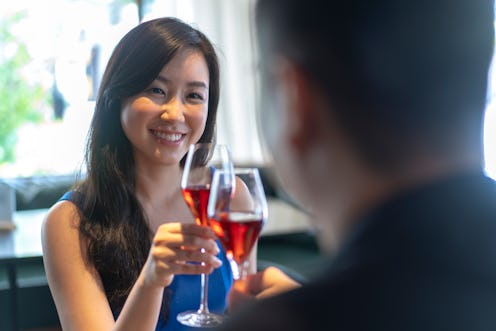 Beautiful young Asian woman having a toast with her partner at a restaurant.
