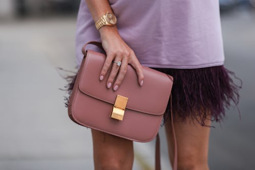 A fashionable woman holding a nude clutch wearing matching nail polish. 