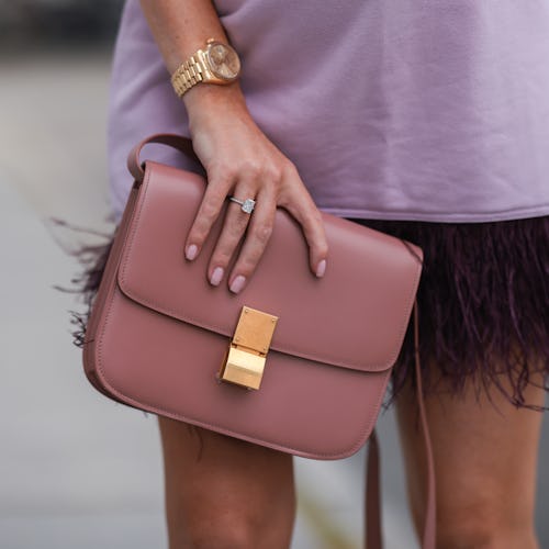 A fashionable woman holding a nude clutch wearing matching nail polish. 