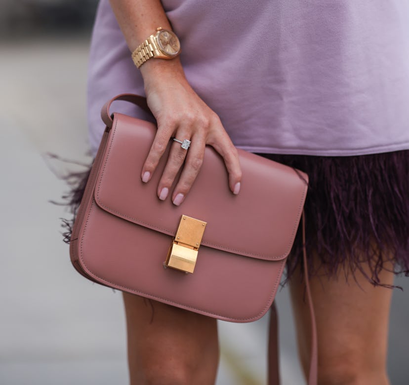 A fashionable woman holding a nude clutch wearing matching nail polish.