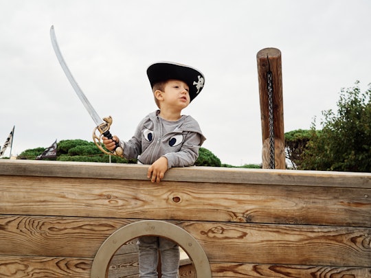 Little boy wearing a pirate hat and smiling inside a pirate ship and holding a sword. Childhood conc...