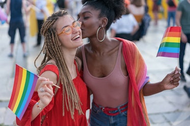 Young pretty women meeting at the pride parade event, hugging and kissing
