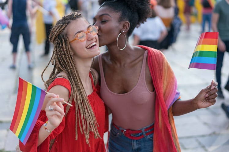 Young pretty women meeting at the pride parade event, hugging and kissing