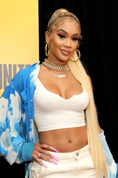 Saweetie wears a slicked-back high ponytail with extensions and sleek, styled baby hair.