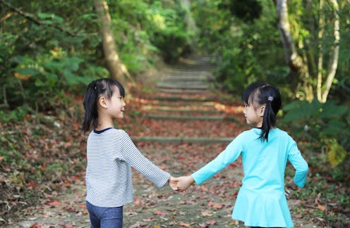 Asian girls playing tung blossom and dead leaves in forest.