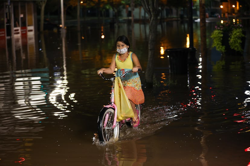 NEW JERSEY, USA - SEPTEMBER 2: A girl rides a bike on the flooded street in the Town of Bound Brook ...