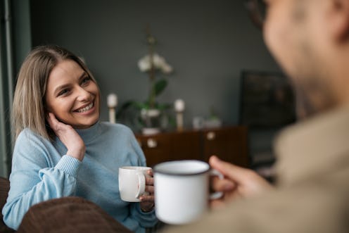 Caucasian man and woman, enjoying themselves at home, having a cup of coffee, talking, bonding and s...