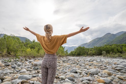 She stands on a rock by the river, forest and mountains on background.
People relaxation and zen-lik...