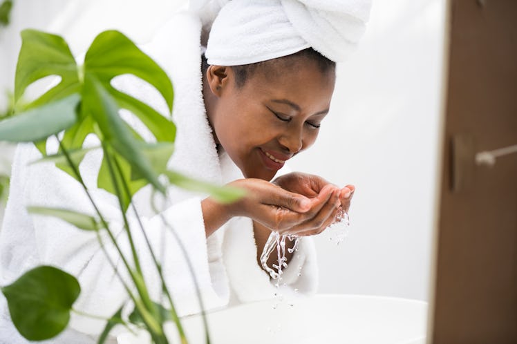 Beautiful black woman washing her face in a bathroom