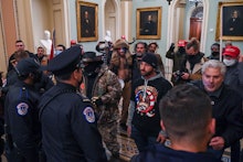 A man wearing a QAnon sweatshirt protests against US Capitol police officers as they try to stop sup...