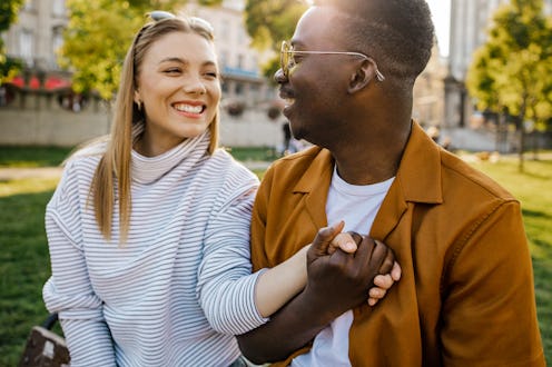 A handsome young African-American man is smiling while his girlfriend is looking at him