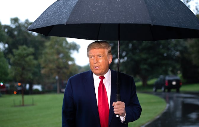 US President Donald Trump holds an umbrella as he speaks to the media under the rain prior to depart...