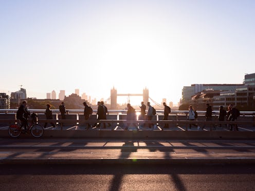 UK, London, crowd of business people walking to work with view of Tower Bridge and Canary Wharf behi...