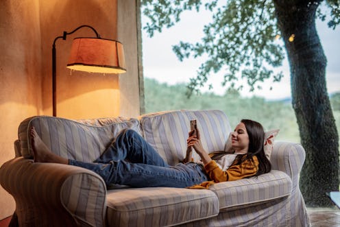 A woman lies on a '70s style sofa switching her professional Instagram account back to personal.