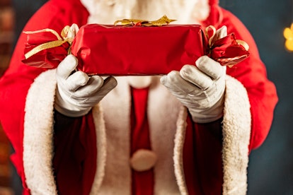 Santa Claus standing while holding holiday christmas gif.