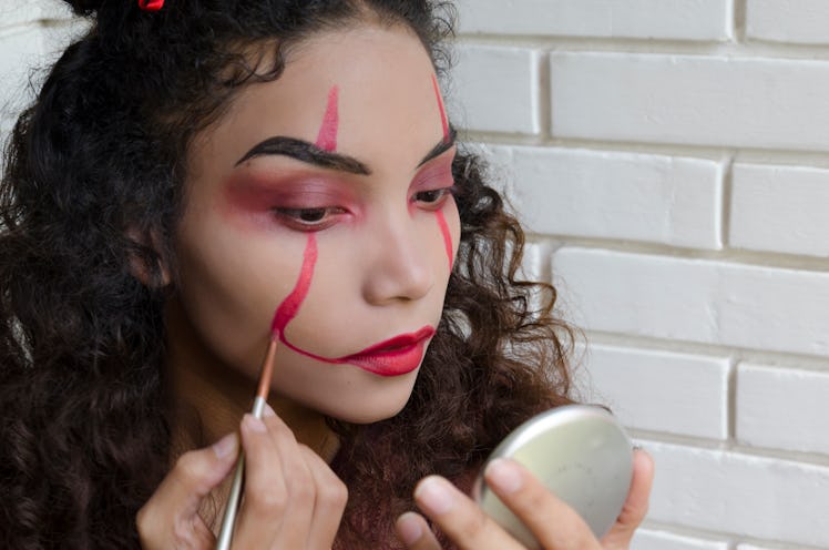 woman putting on Pennywise clown makeup for Halloween, inspired by Stephen King's It