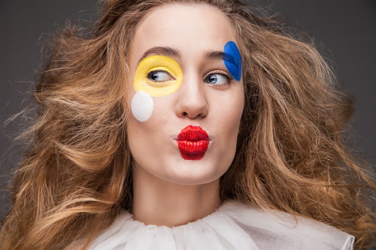 female clown with colorful makeup in white ruffled collar