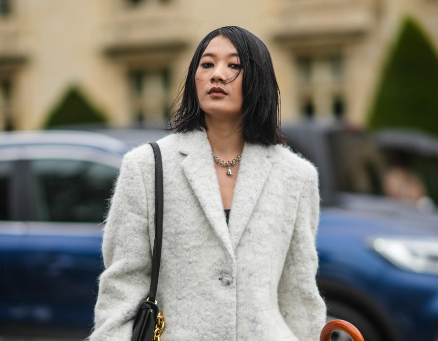 PARIS, FRANCE - OCTOBER 05: A guest wears a silver large chain pendant necklace, a white fluffy long...