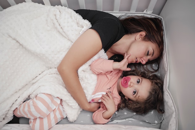mom sleeping in crib with little girl