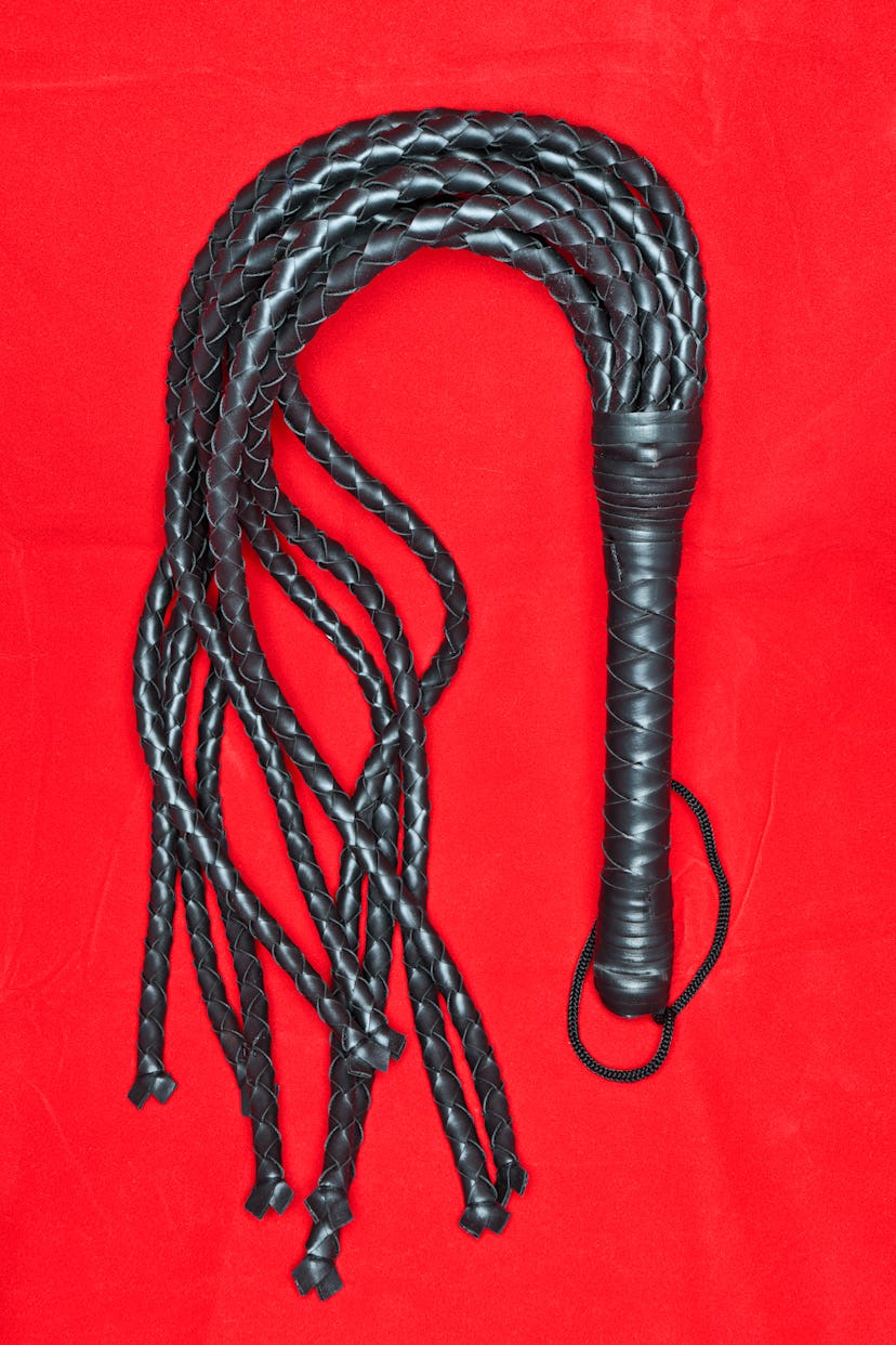 Fetish whip on red background