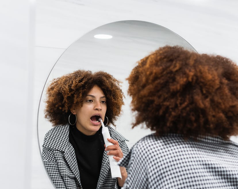 woman brushing teeth with electric toothbrush, how does pregnancy affect teeth