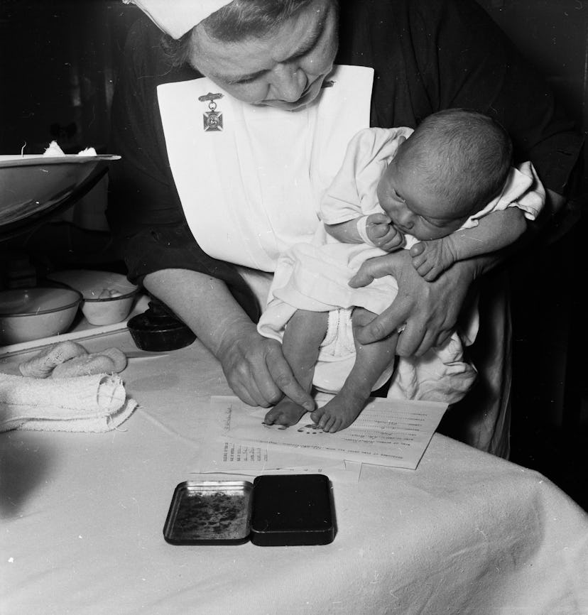 A nurse stamps the footprint of a baby in a vintage maternity ward.